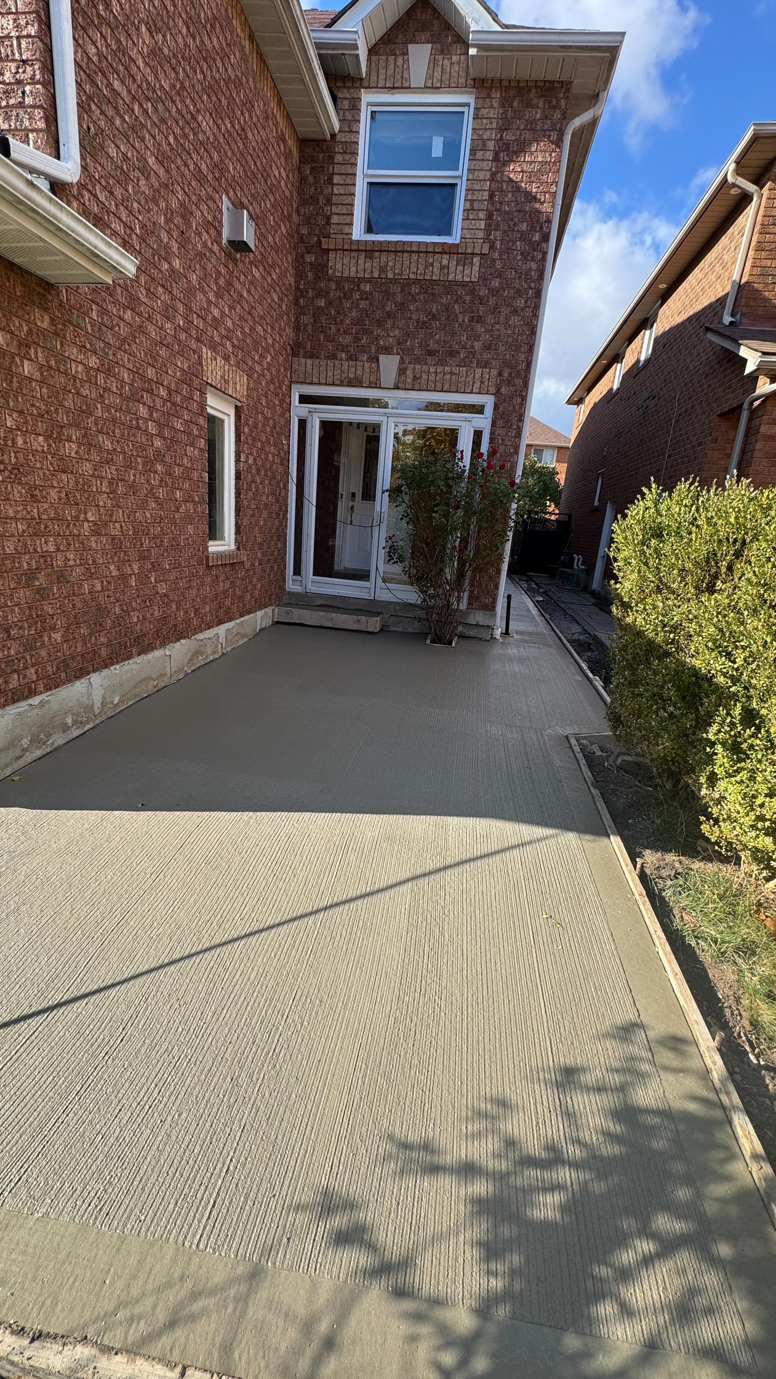 New poured concrete walkway alongside a brick home